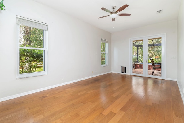 empty room with ceiling fan, light wood-type flooring, and french doors