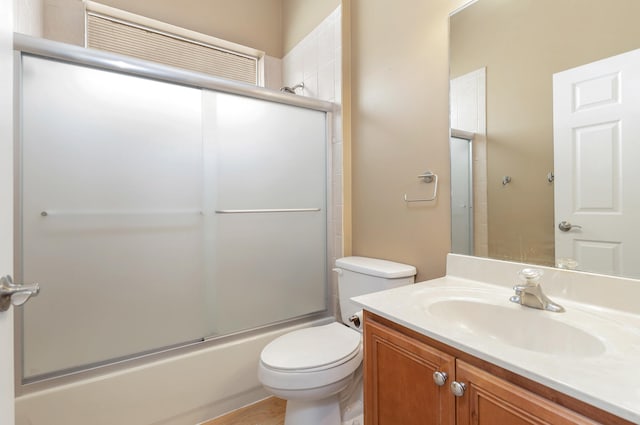 full bathroom with enclosed tub / shower combo, vanity, and toilet