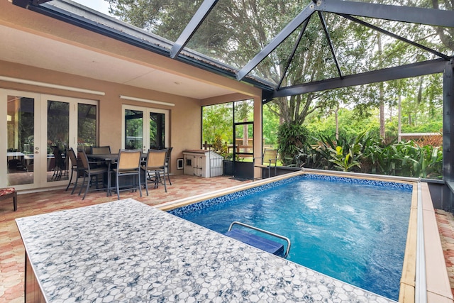 view of swimming pool with glass enclosure, a patio area, and french doors