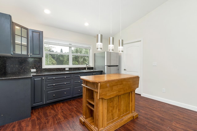 kitchen featuring lofted ceiling, hanging light fixtures, stainless steel fridge, backsplash, and dark hardwood / wood-style floors