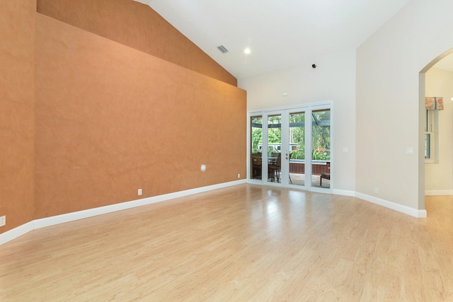 unfurnished room with french doors, light wood-type flooring, and high vaulted ceiling