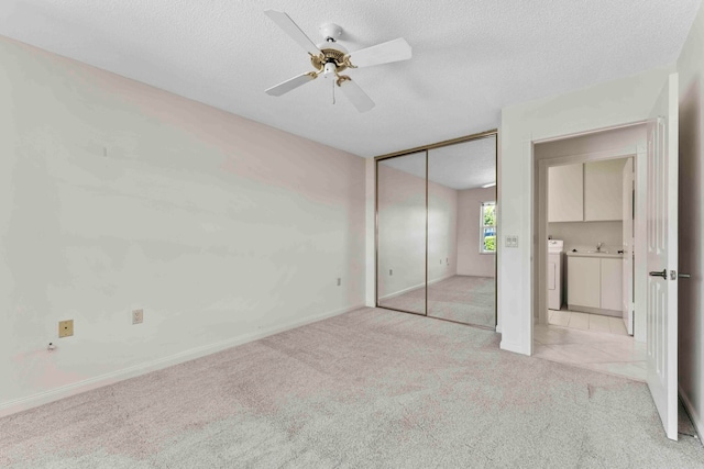 unfurnished bedroom with a closet, a textured ceiling, ceiling fan, sink, and light colored carpet