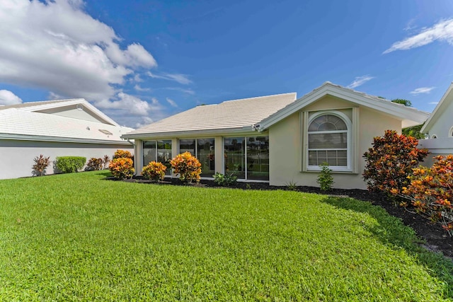 rear view of property with a sunroom and a lawn