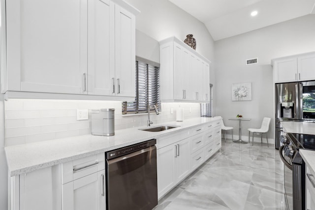 kitchen with light stone counters, sink, white cabinets, vaulted ceiling, and stainless steel appliances