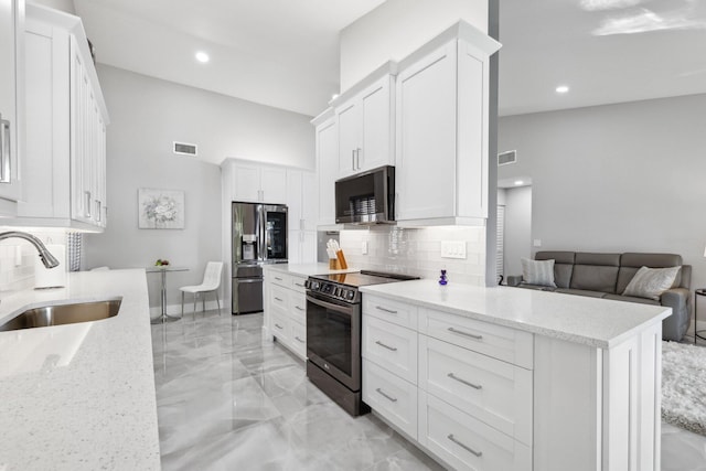 kitchen with light stone counters, tasteful backsplash, sink, white cabinetry, and black appliances