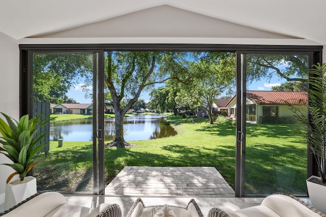 sunroom / solarium with a water view, vaulted ceiling, and a healthy amount of sunlight