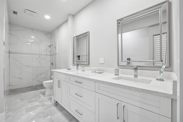 bathroom with tiled shower, vanity, and toilet