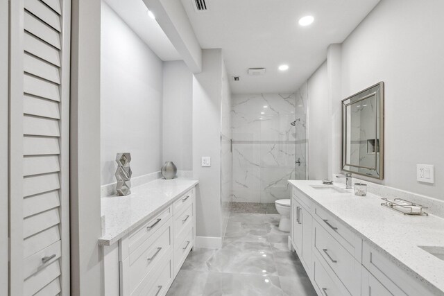 bathroom with tiled shower, vanity, and toilet