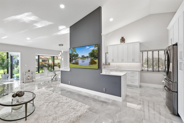 kitchen featuring stainless steel refrigerator, white cabinetry, vaulted ceiling, and pendant lighting