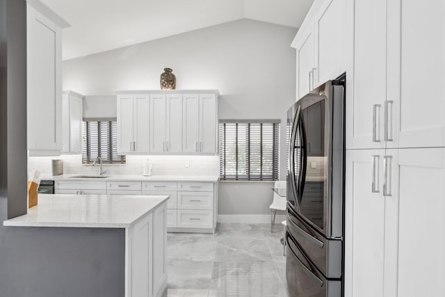 kitchen featuring stainless steel refrigerator, lofted ceiling, sink, and white cabinets