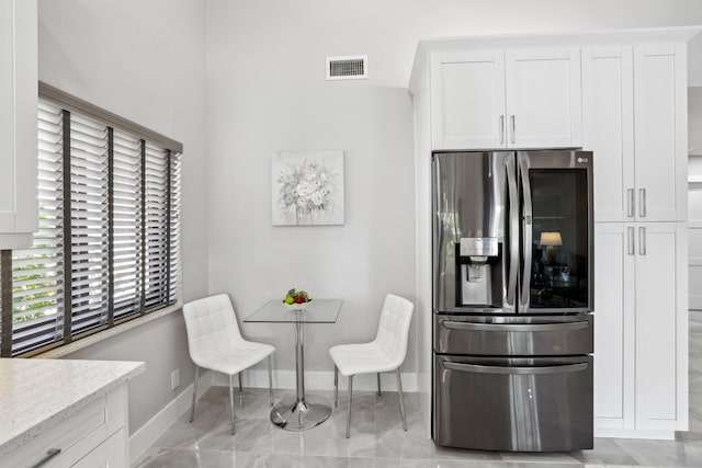 kitchen with white cabinets, light stone countertops, and stainless steel fridge with ice dispenser