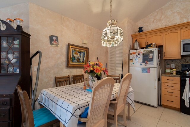 dining room with vaulted ceiling, an inviting chandelier, and light tile patterned floors