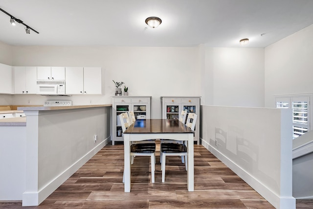 dining area with track lighting and dark wood-type flooring