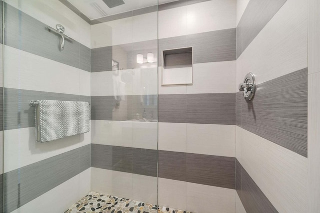 bathroom with a tile shower and tile walls