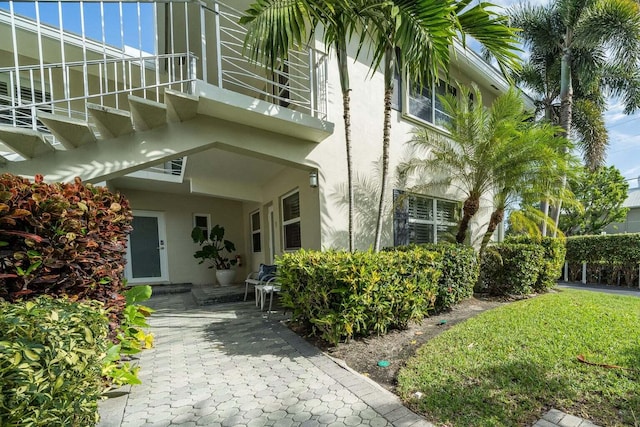 entrance to property featuring a patio area, a lawn, and a balcony