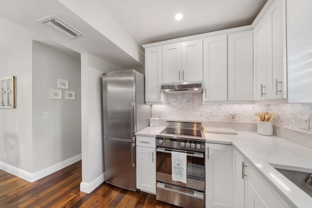 kitchen featuring appliances with stainless steel finishes, sink, dark hardwood / wood-style flooring, white cabinetry, and decorative backsplash