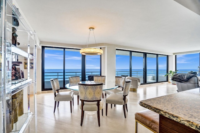 kitchen featuring light stone counters, kitchen peninsula, beverage cooler, decorative light fixtures, and a water view