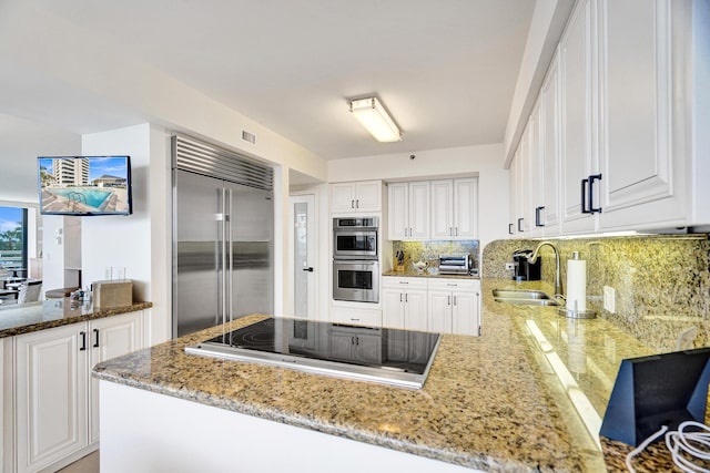 kitchen featuring white cabinetry, built in refrigerator, and sink