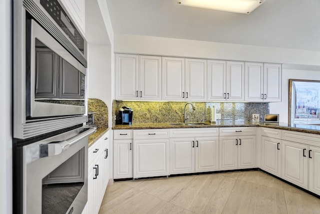 kitchen featuring backsplash, white cabinetry, and sink