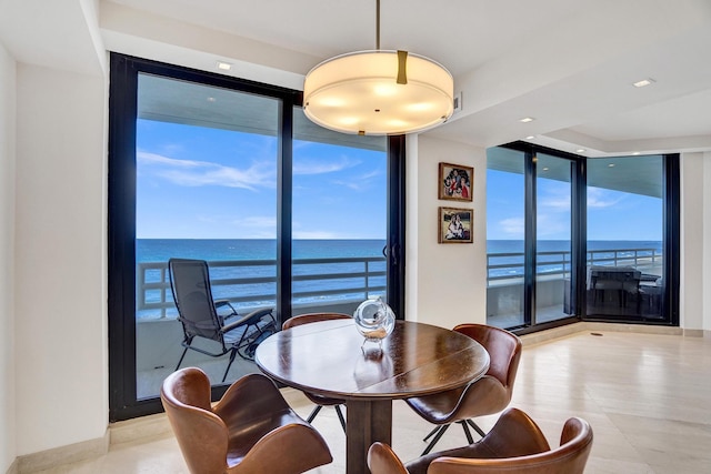 dining room with floor to ceiling windows, a water view, and plenty of natural light