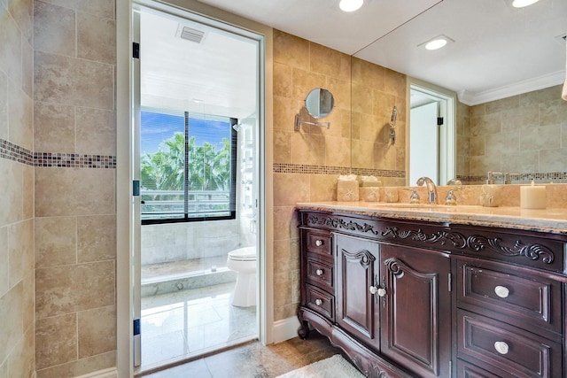 bathroom with tile walls, a shower, vanity, and toilet