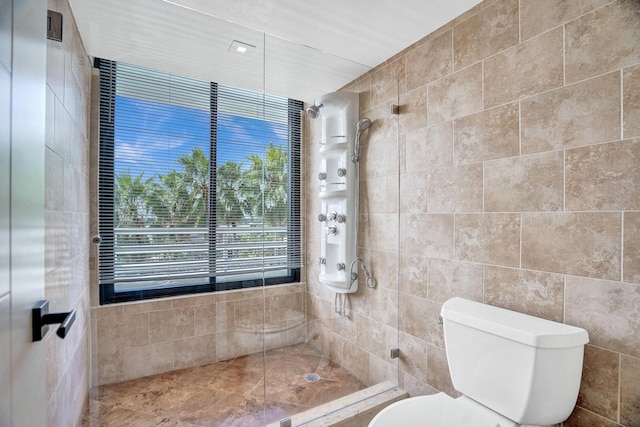 bathroom featuring tile walls, toilet, and tiled shower