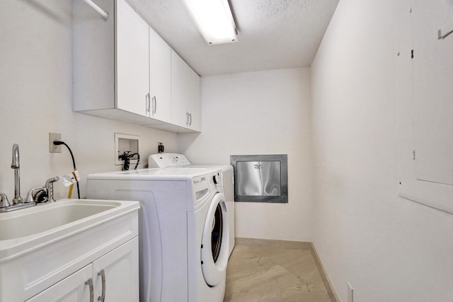 washroom with cabinets, a textured ceiling, washing machine and clothes dryer, and sink