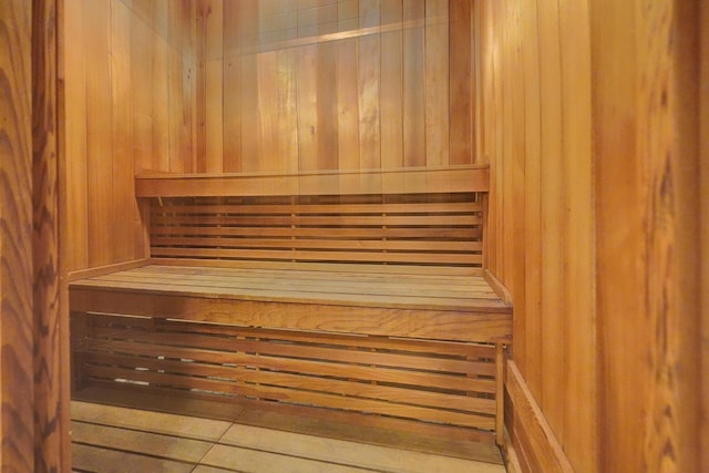 view of sauna / steam room with wood walls and tile patterned floors