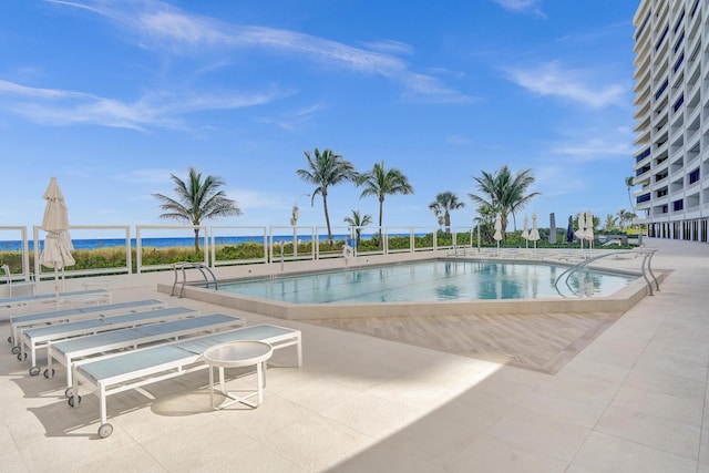 view of swimming pool with a patio and a water view