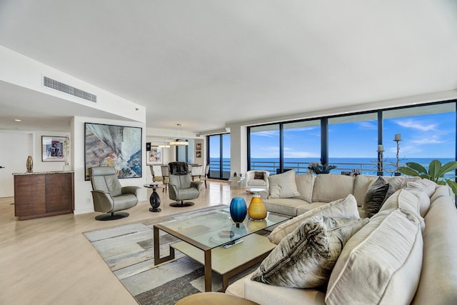 living room featuring light wood-type flooring, a water view, and expansive windows