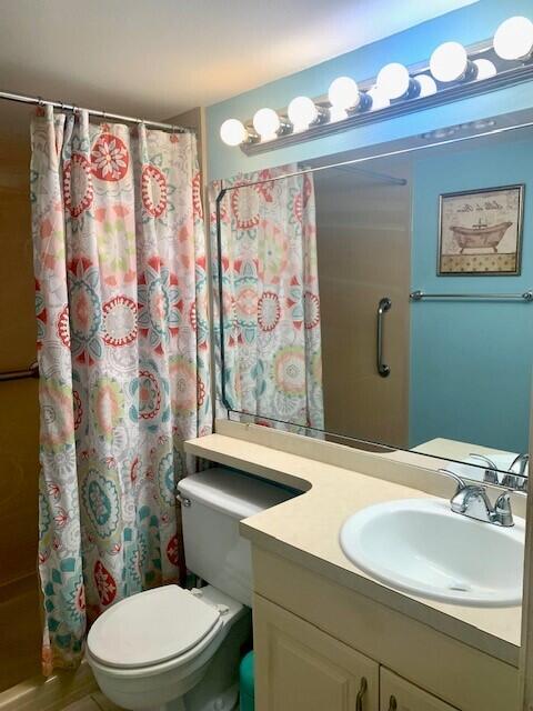 bathroom featuring toilet, vanity, and a shower with shower curtain