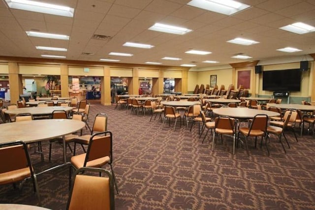 carpeted dining space featuring a paneled ceiling