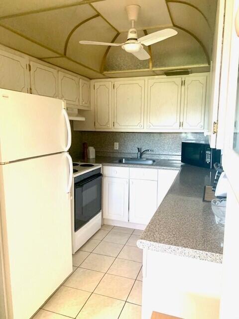 kitchen featuring exhaust hood, light tile patterned floors, backsplash, sink, and white appliances