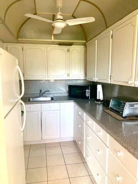 kitchen featuring sink, white cabinets, light tile patterned flooring, and white refrigerator