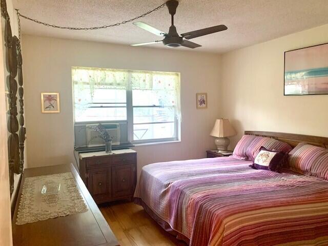 bedroom featuring a textured ceiling, wood-type flooring, and ceiling fan