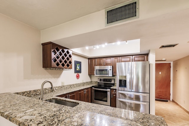 kitchen with kitchen peninsula, light stone countertops, sink, and appliances with stainless steel finishes