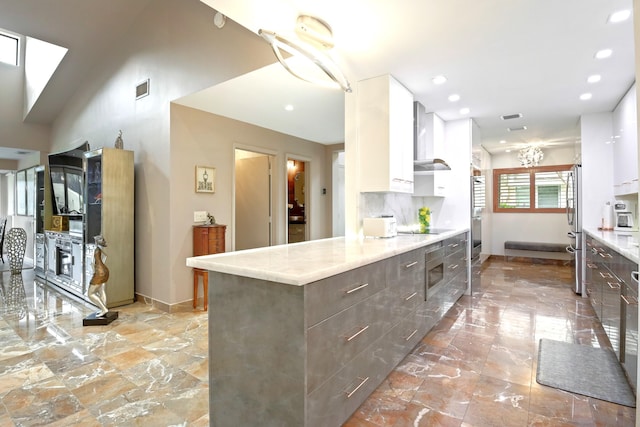 kitchen with decorative backsplash, dark brown cabinetry, stainless steel appliances, wall chimney range hood, and white cabinetry