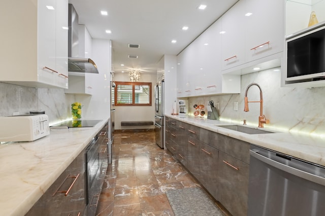 kitchen featuring stainless steel appliances, white cabinetry, wall chimney exhaust hood, and sink