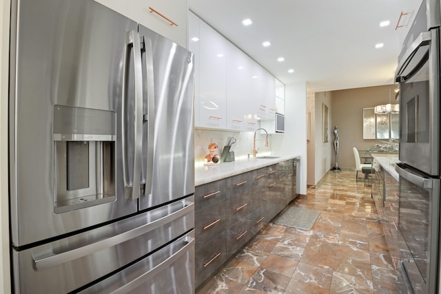 kitchen with stainless steel refrigerator with ice dispenser, backsplash, sink, white cabinets, and stainless steel refrigerator