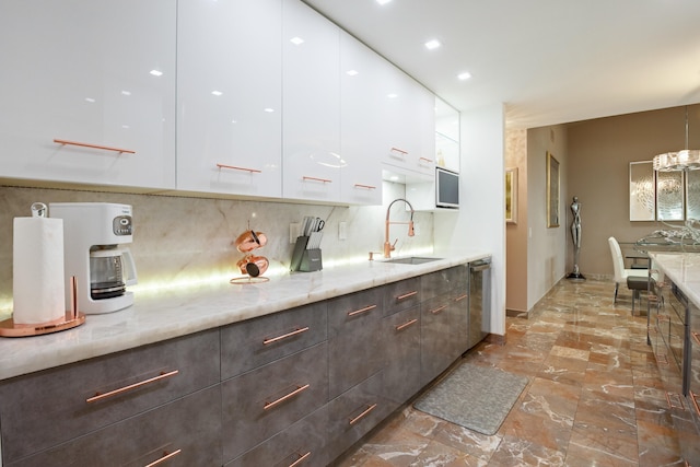 kitchen featuring white cabinetry, sink, dishwasher, light stone countertops, and tasteful backsplash