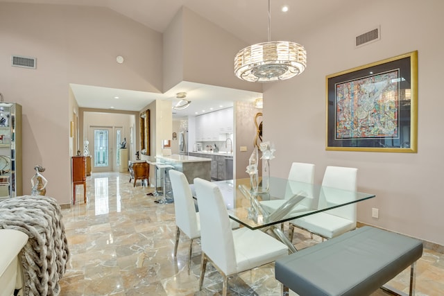 dining room with sink, high vaulted ceiling, and a chandelier