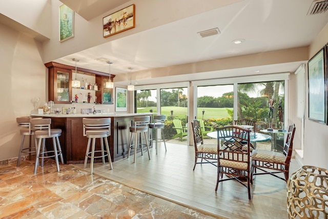 dining space with bar and light wood-type flooring