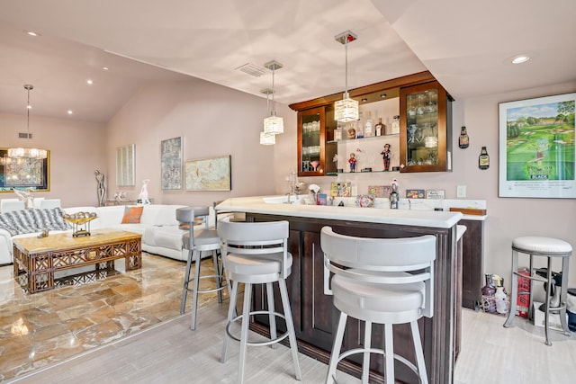 kitchen with a breakfast bar, hanging light fixtures, vaulted ceiling, light hardwood / wood-style flooring, and kitchen peninsula