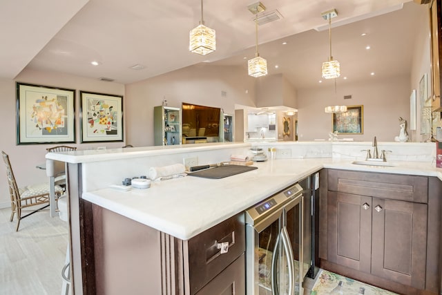 kitchen featuring decorative light fixtures, dark brown cabinets, sink, and beverage cooler