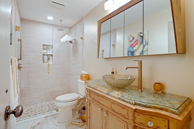 bathroom with vanity, toilet, and tiled shower