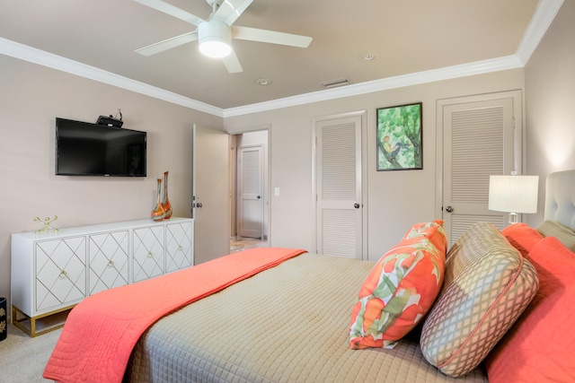 carpeted bedroom featuring two closets, ceiling fan, and ornamental molding