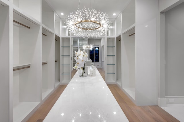 spacious closet featuring light hardwood / wood-style flooring and a notable chandelier