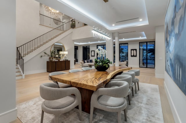 dining area with light hardwood / wood-style floors, a tray ceiling, and an inviting chandelier