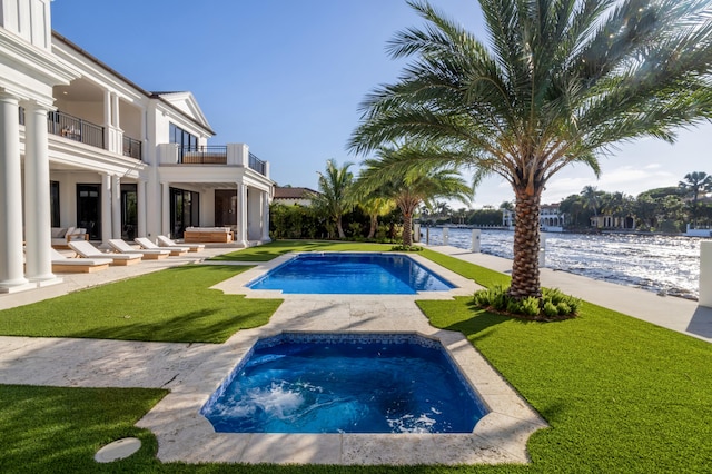 view of pool featuring a patio area, a water view, a lawn, and a jacuzzi