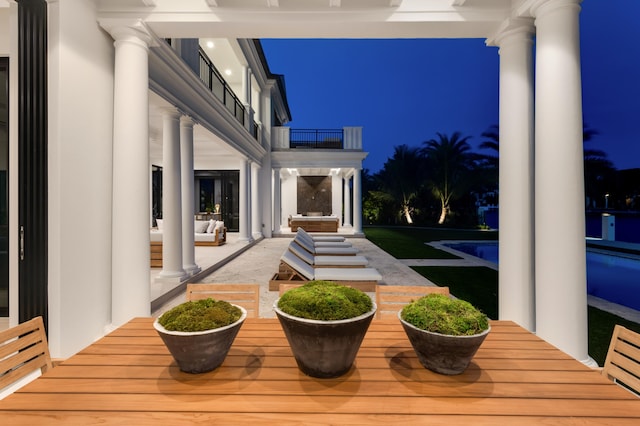 patio at twilight featuring a balcony